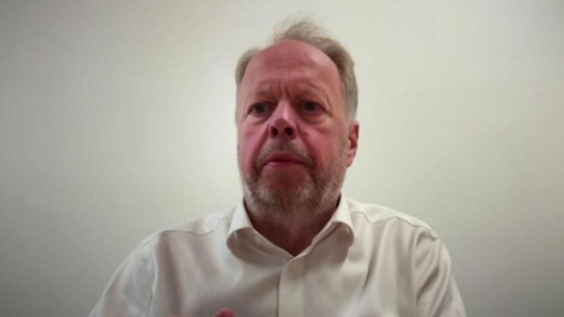 A man with fair hair and a beard in a white shirt against a white background