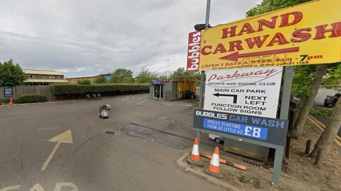 Entrance to a car wash with a sign that reads "hand carwash".