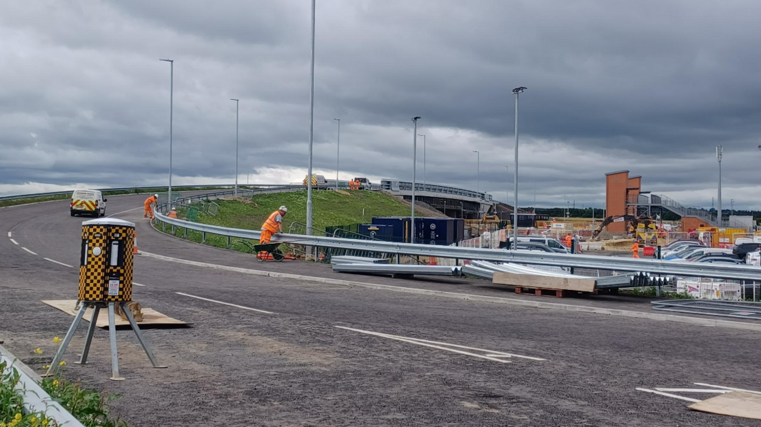 Workers are putting the final touches to a new road bridge over a railway station.