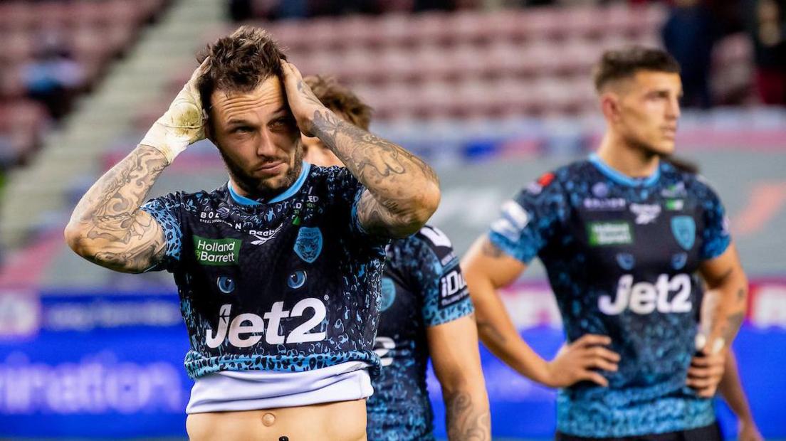 A Leigh Leopards player has his head on his hands and another his arms on his sides