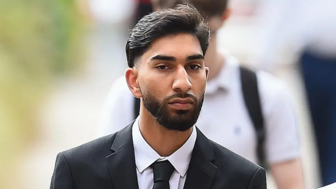 An unsmiling head-and-shoulders shot of Mohammed Amaaz, wearing a black suit, white shirt and black tie, arriving at court