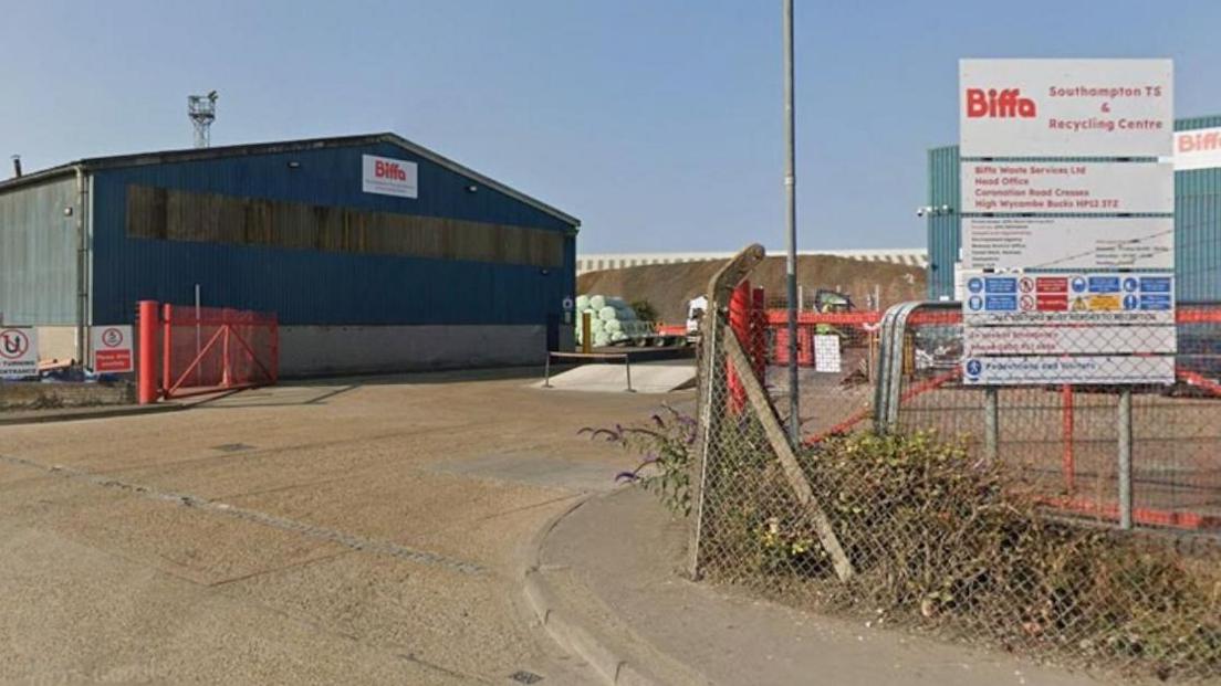 A large blue depot on an industrial estate with a Biffa sign on the gable end. A white sign with red writing, says 'Biffa Southampton TS and recycling centre'