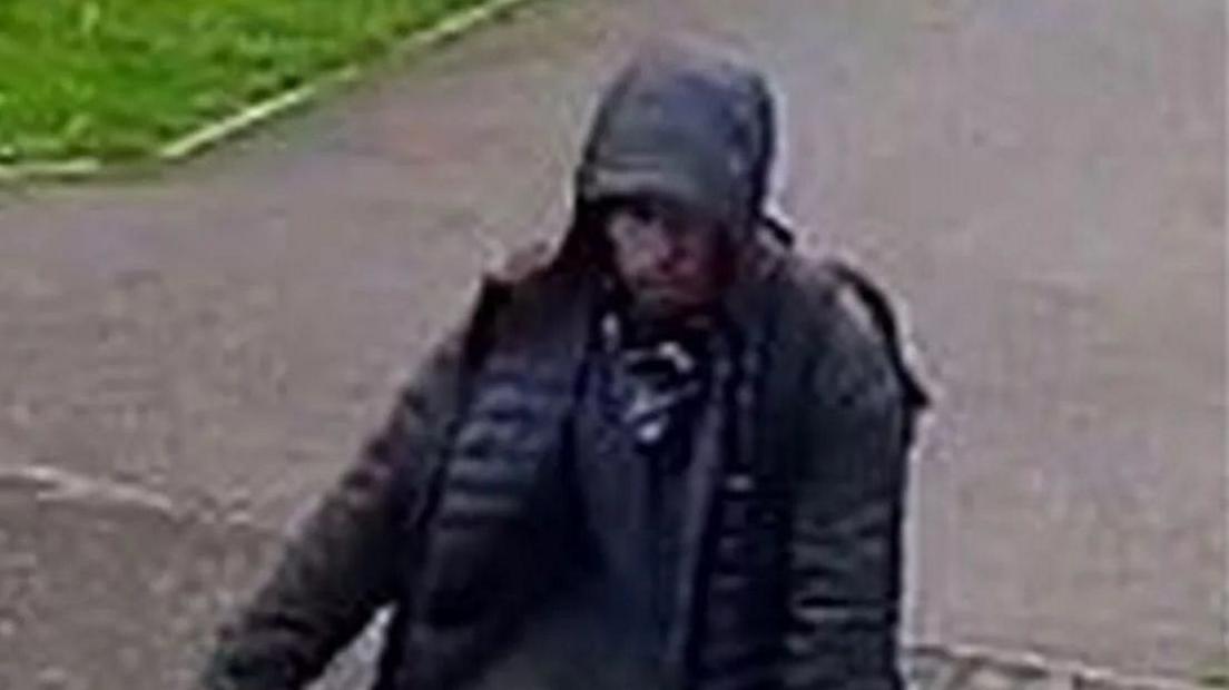 A grainy CCTV still of a hooded man on a pushbike