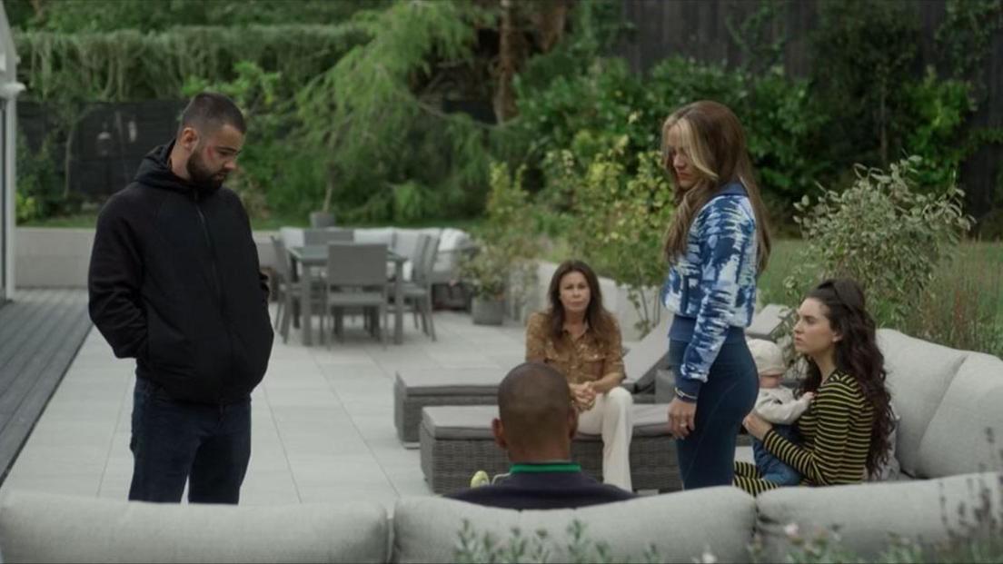The Phelan family of five - plus baby - are seen sitting on the garden sofa or standing up during a meeting.