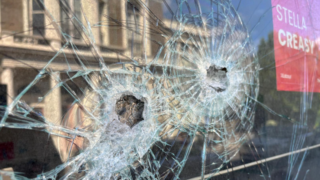 Two holes in the window of Stella Creasy's office, with a red sign saying Stella Creasy to the left of where the glass has shattered