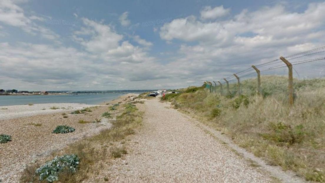 Shingle path and beach with expanse of water to the left.