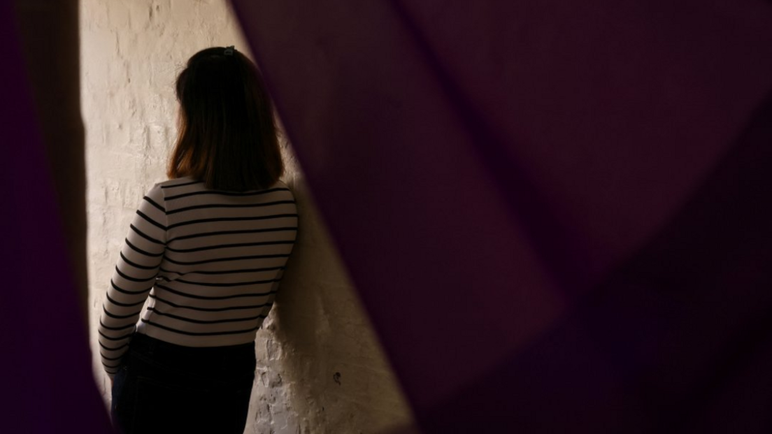 Generic image of an anonymous woman thought to be a victim of modern slavery, posing with back turned and face obscured on a staircase