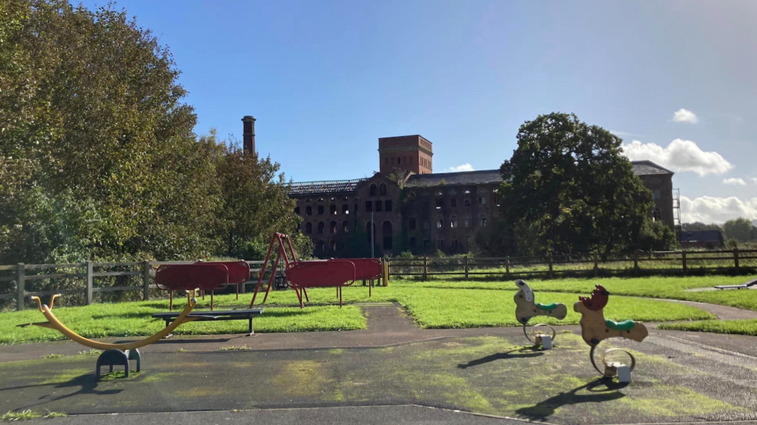 A view of the Tonedale Mill with a play park in the foreground