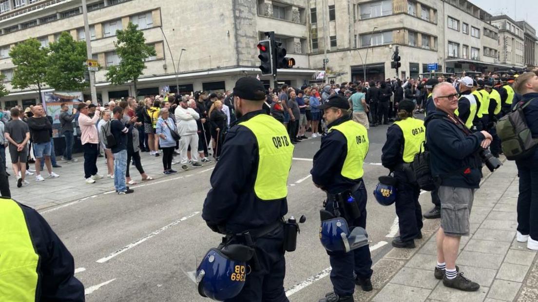 Police in high-vis jackets face a group of protesters in the centre of Plymouth