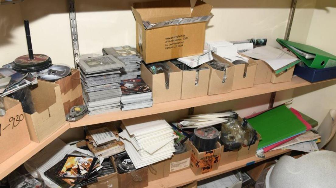 Shelves full of boxes of CDs and pamphlets. The image does not show the exact offensive material, as most is upside-down or stacked.