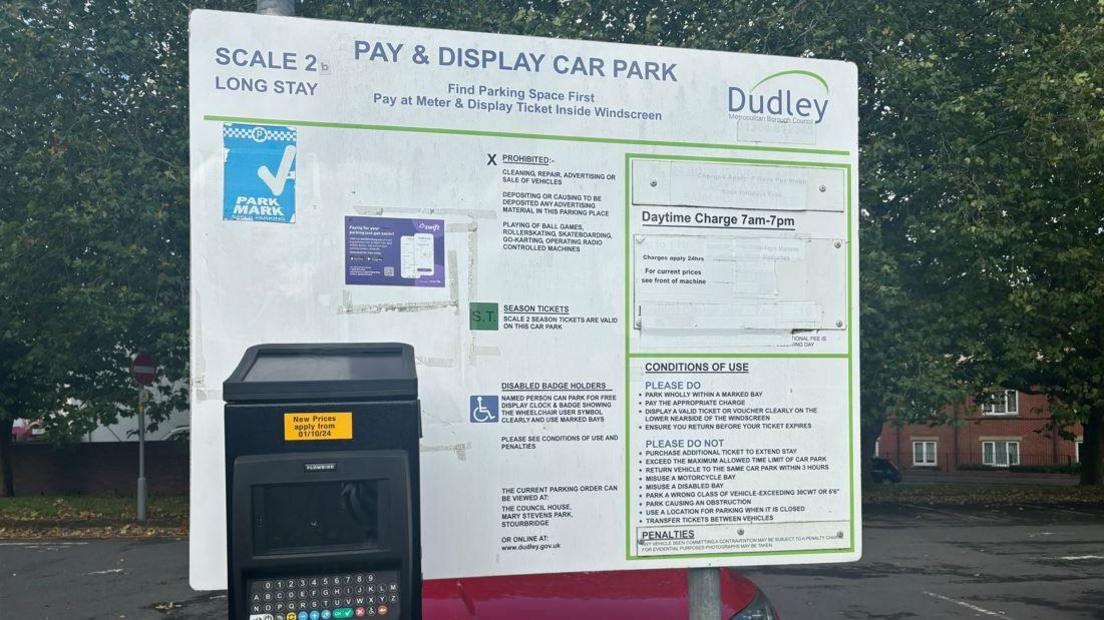 Photo of a car parking pay machine in front of a sign explaining charges