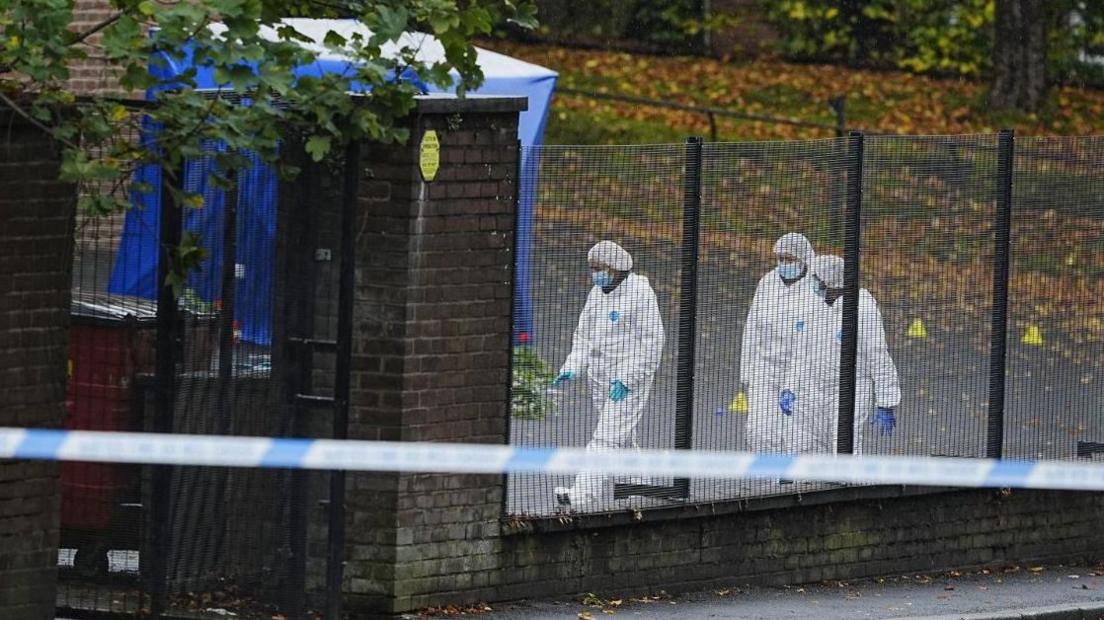 Three forensic officers wearing white overalls and masks remain at the scene near Heaton Park Hebrew Congregation synagogue. A tent has been erected and a police cordon is in place