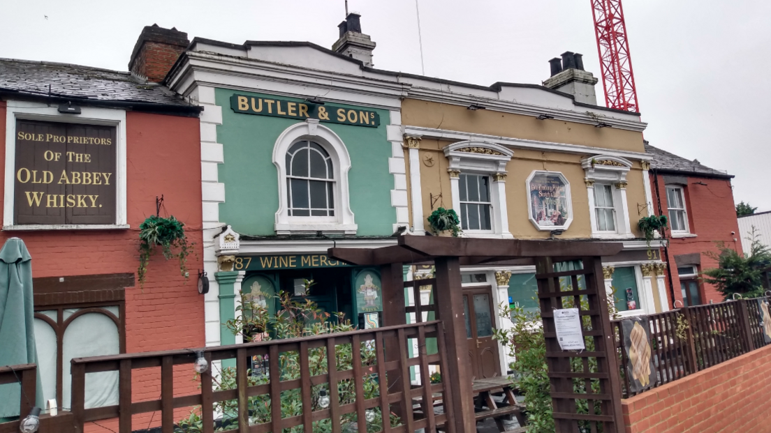 The Butler Pub in reading is a red, green and yellow edwardian looking building.