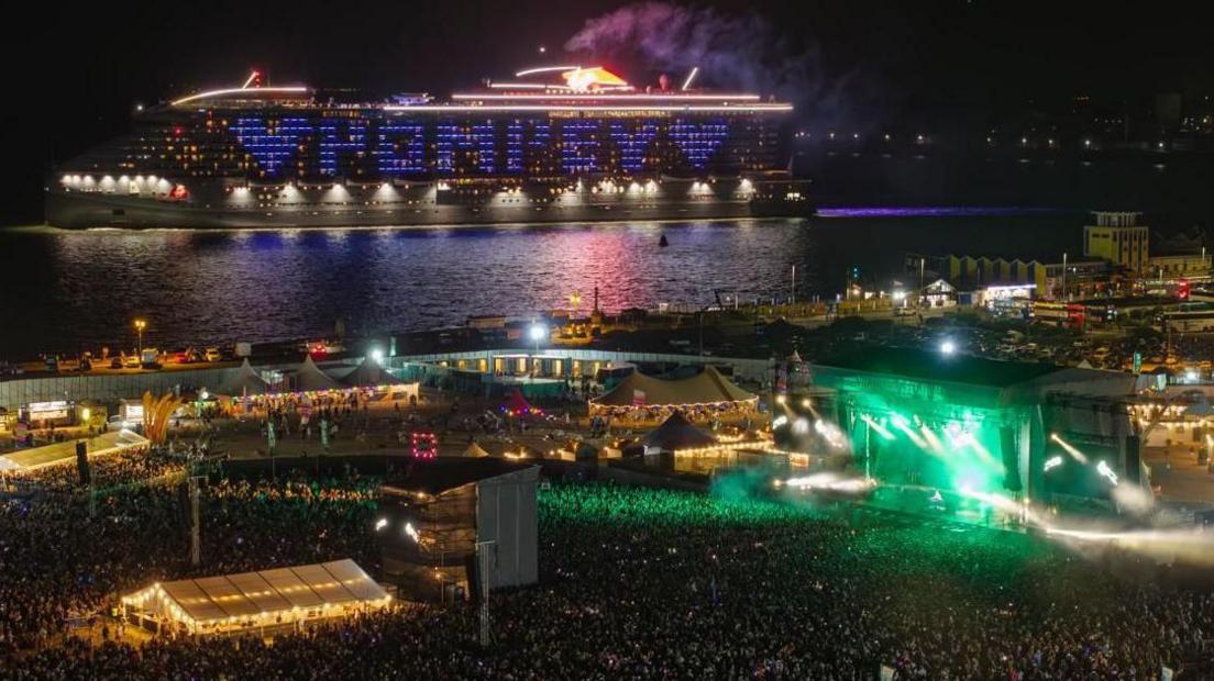 A cruise ship sets sail from Portsmouth on Friday evening to the backdrop of Fatboy Slim’s set. Its side is illuminated to spell "Pompey" with a heart.