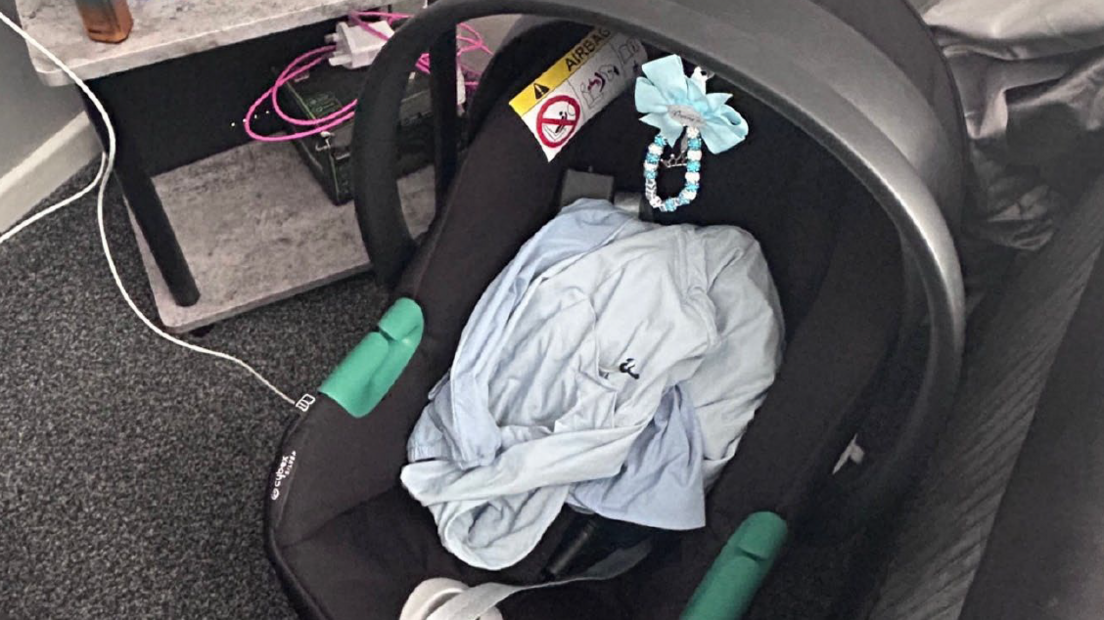 A black and grey baby's car seat with a blue blanket on it