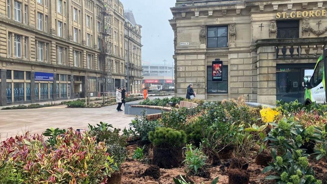 A raised flower bed on Bridge Street in Bradford with the entrance to the city's St George's Hall in the background and newly laid paving to the left of the flower bed