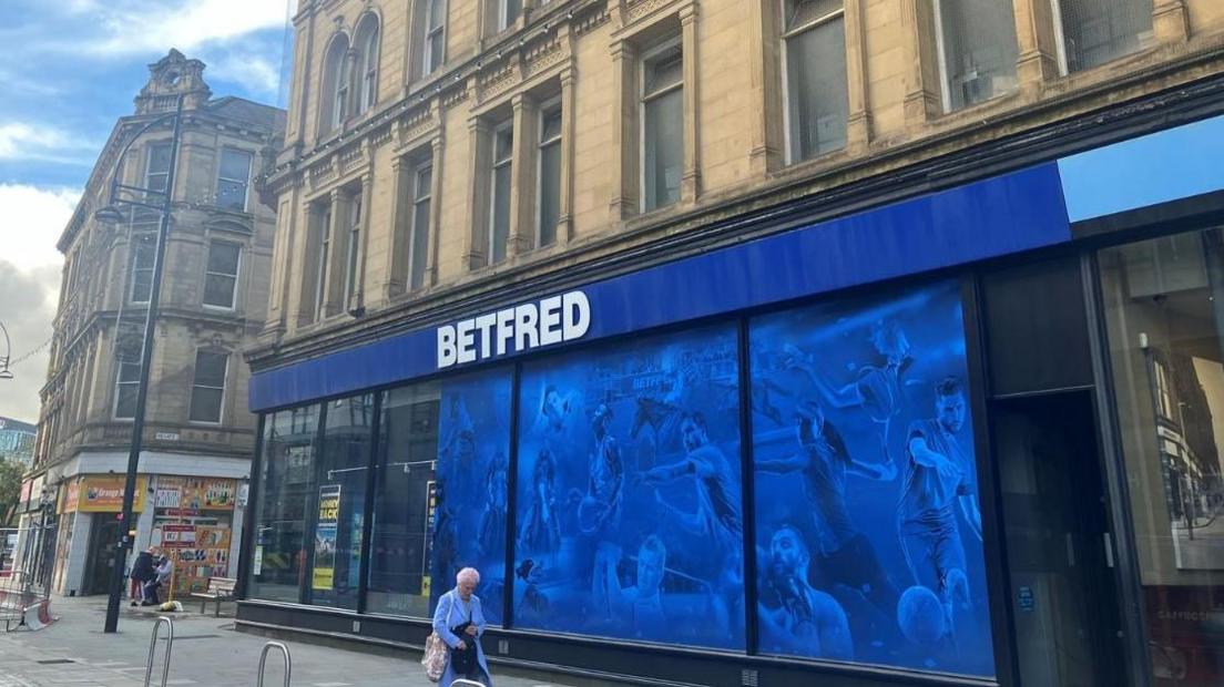 A large blue vinyl sign hanging in the window of a department store on market Street