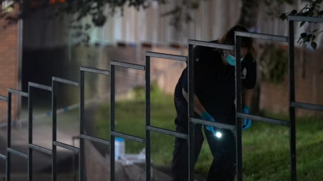 A police officer searching a crime scene in Crawley by torchlight