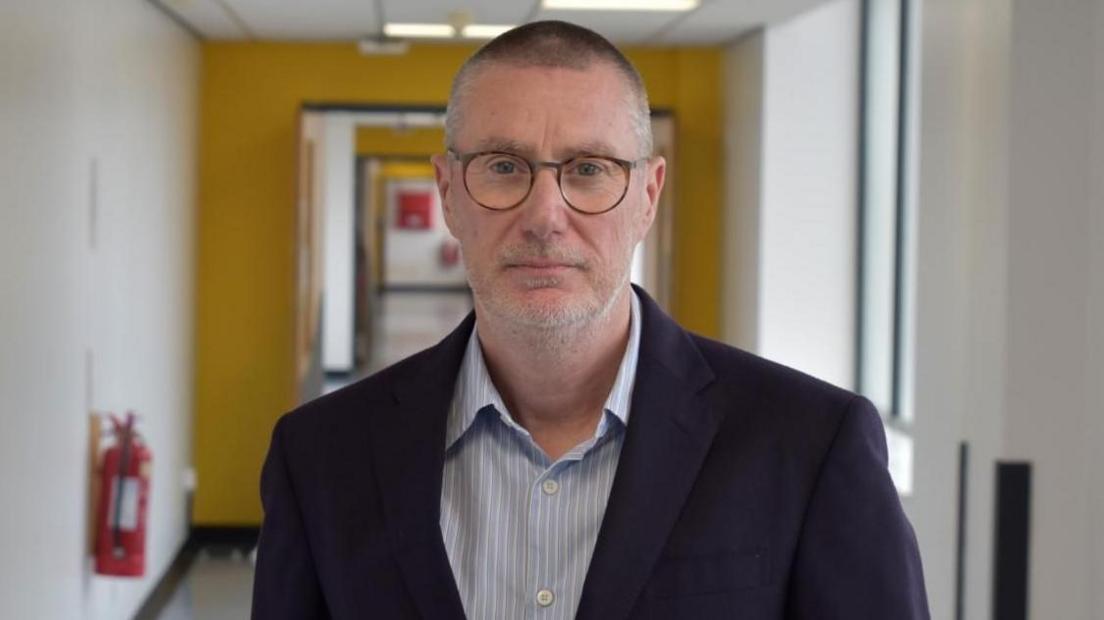 Anthony May wearing jacket and shirt in hospital corridor