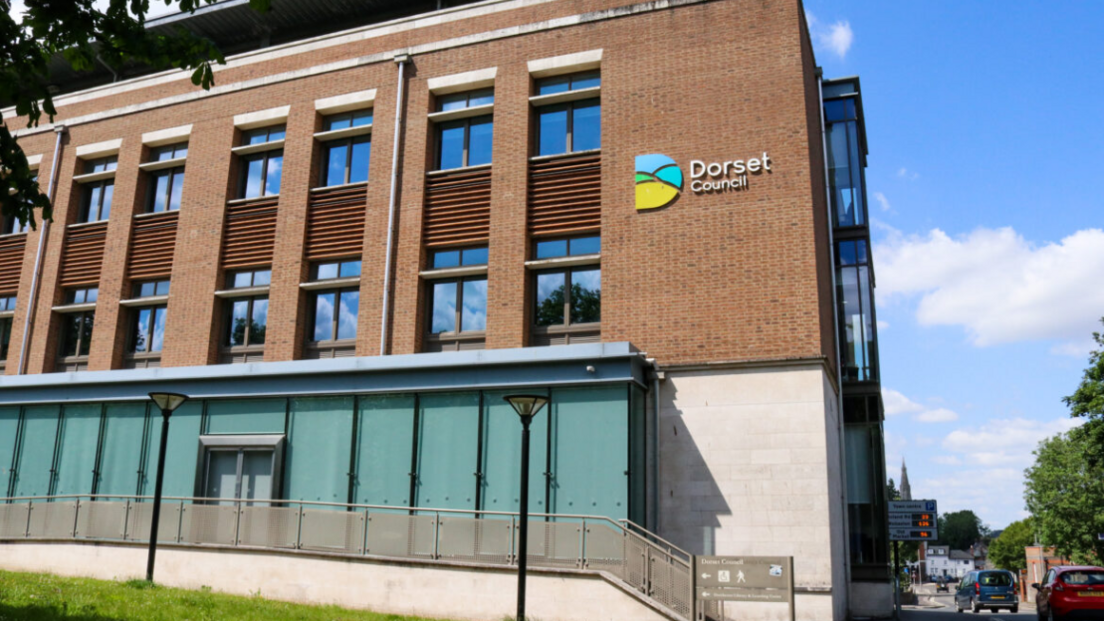 Part White and Red Brick building with a sign which says 'Dorset Council' on it.