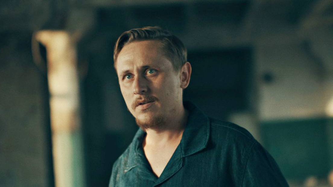 Dima, wearing a blue collared t-shirt, speaks to the BBC in an undisclosed warehouse.