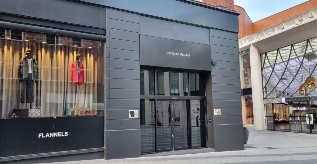 An exterior shot of The Man Behind the Curtain in central Leeds - a black fronted building with glass double doors.