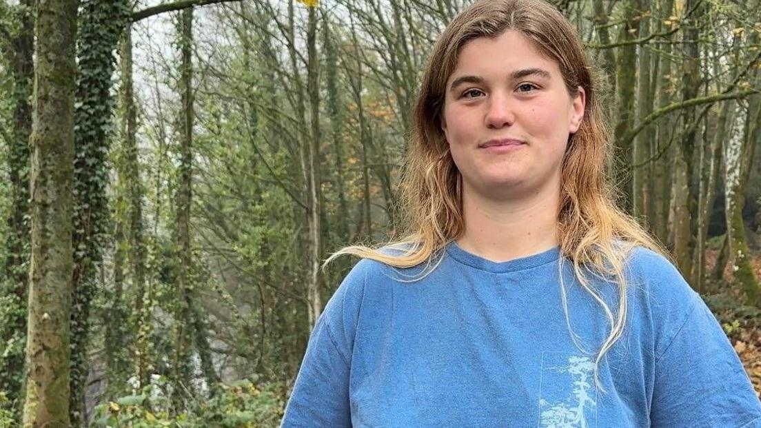A woman in a blue t-shirt in some woodland