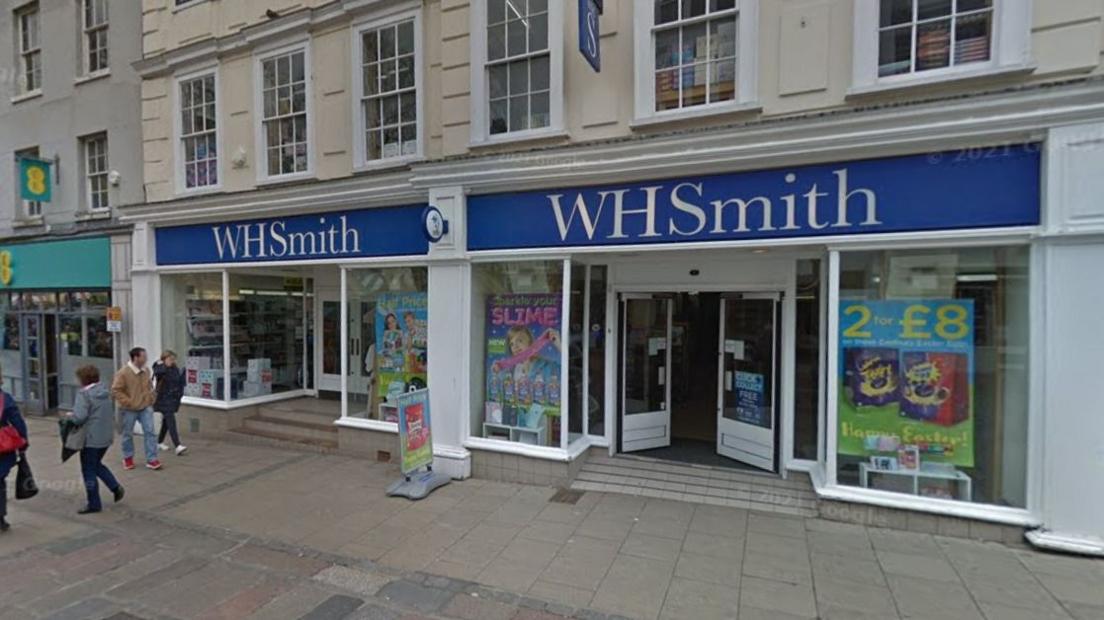 WH Smith photographed outside from the pavement, with a number of people walking by the store. 