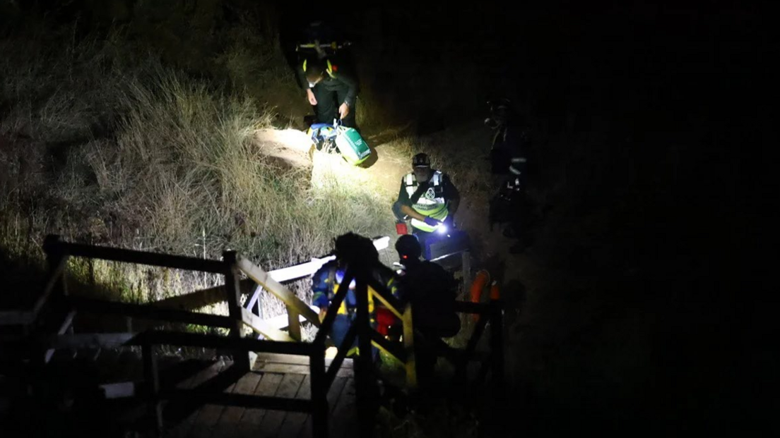 Emergency services wearing head torches on a beach