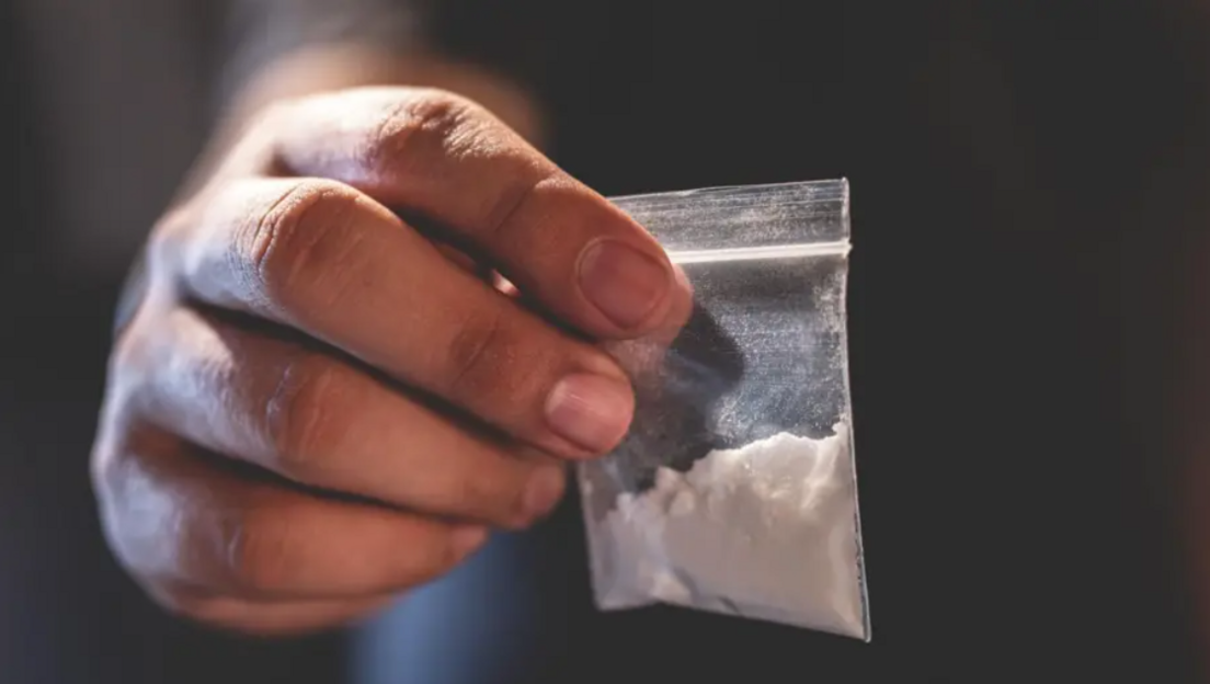 A hand holding white powder in a packet (stock image)