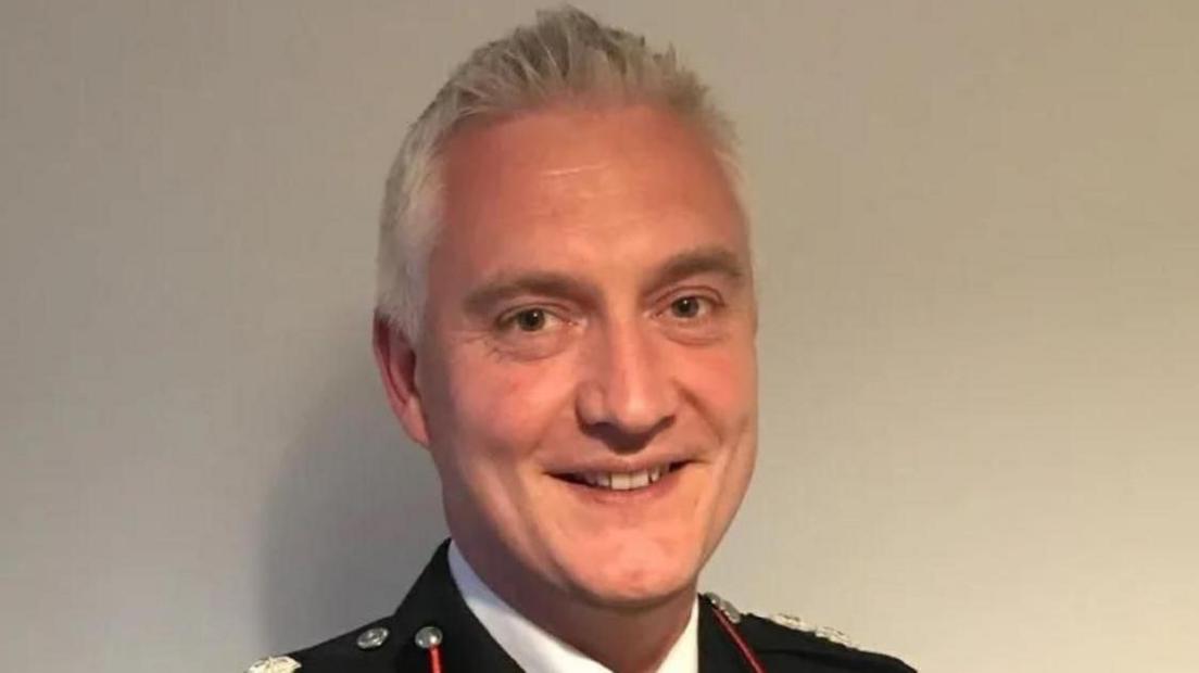 Ben Brook in his fire officer uniform in front of a white wall 