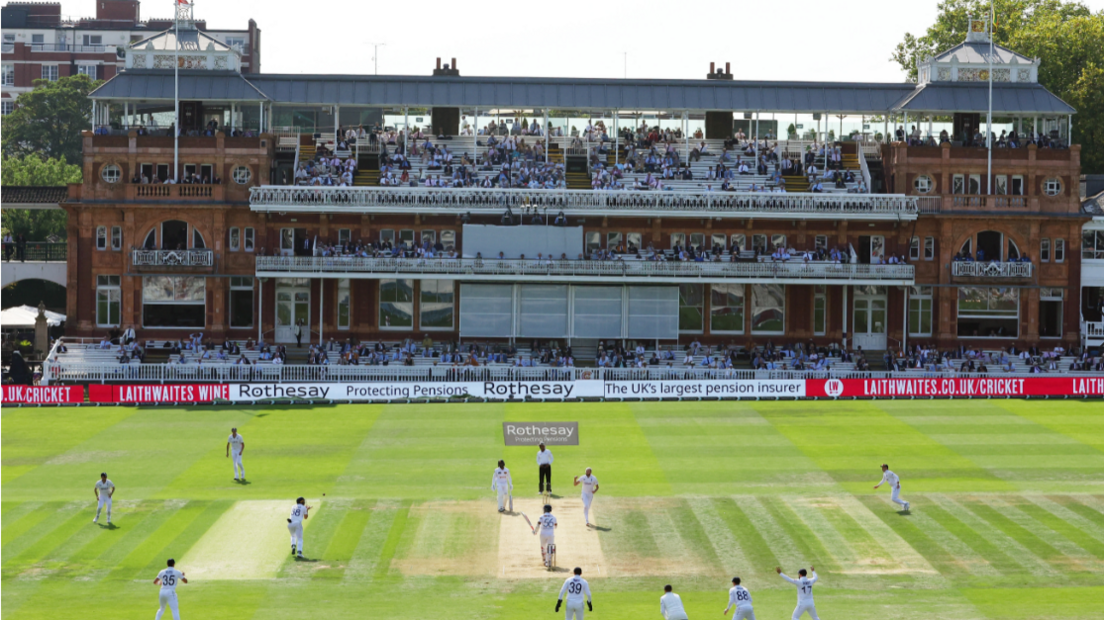 A landscape shot of the cricket pitch at Lords, with batters and fielders in position. 