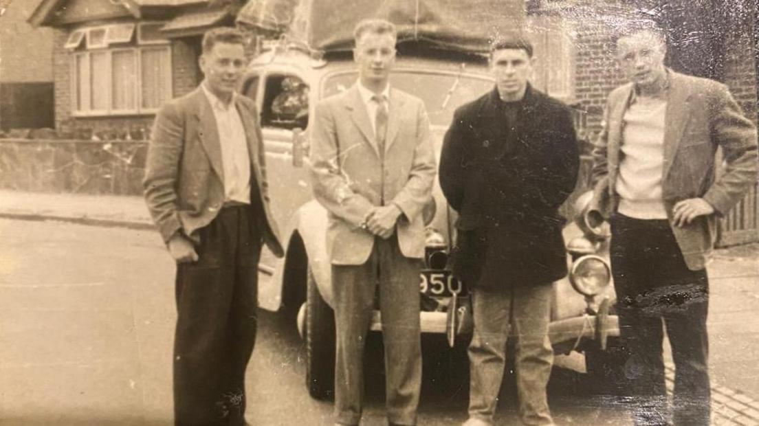 Four men pose in front of their second-hand Ford motor car in June 1959, for a photo that was taken outside of St Monica's Avenue in Luton.