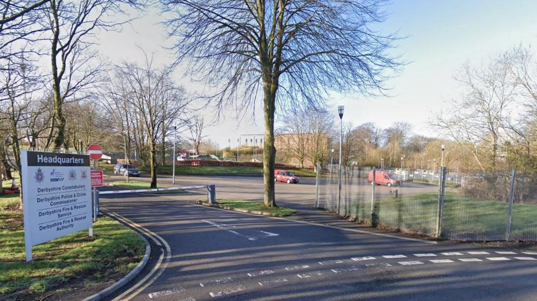 Main entrance to Derbyshire Police headquarters, showing a large sign by a road leading into a car park