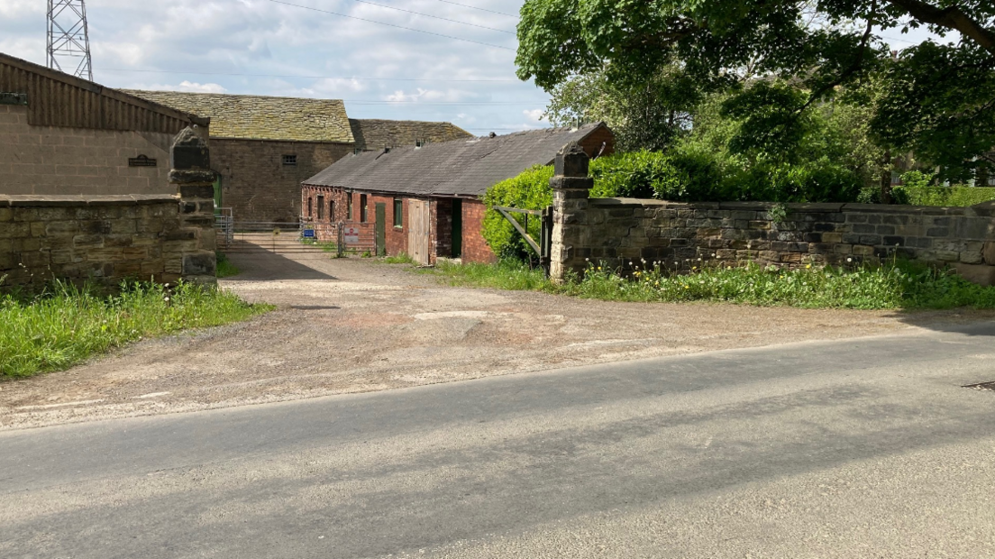 Farm buildings and a barn off a main road.