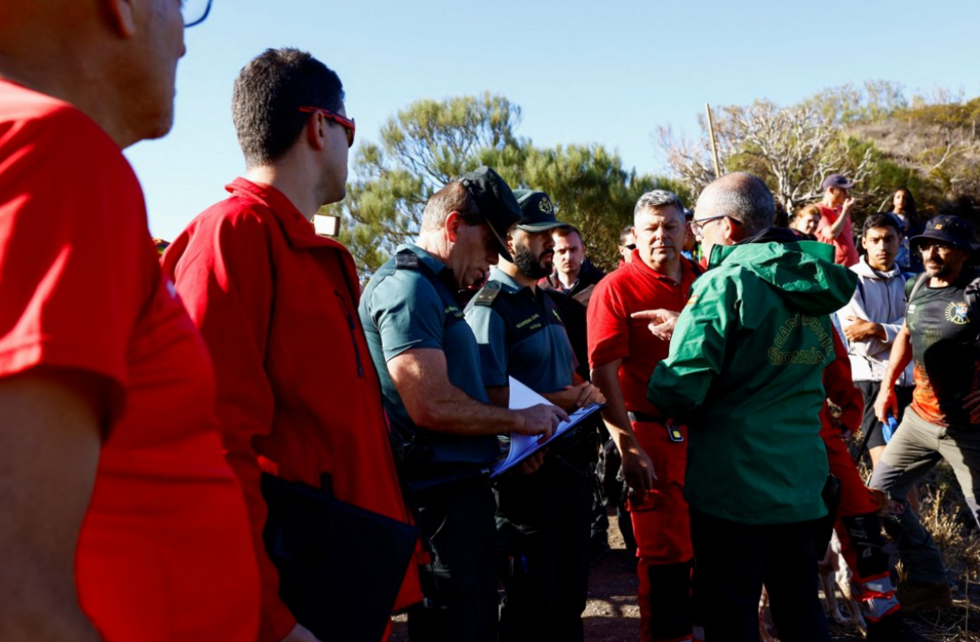 Guardia Civil agent Cipriano Martin, wearing a green jacket, speaks with search volunteers wearing high-visibility red t-shirts and fleeces, before beginning the search for missing Jay Slater in the Masca ravine on June 29, the day before the police search was called off.