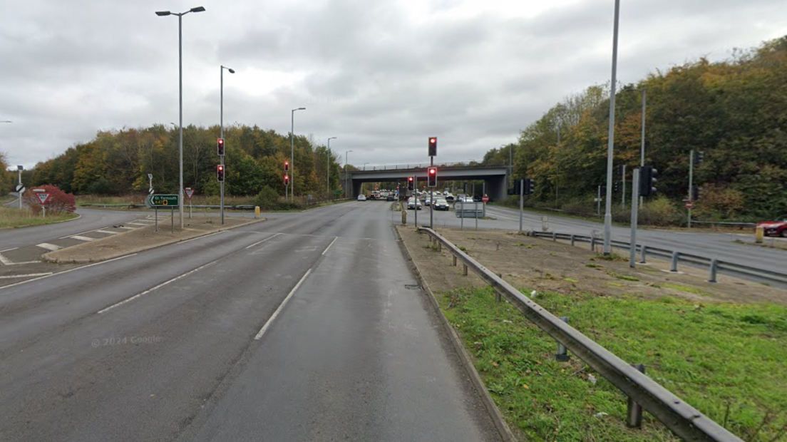 Slip roads coming off the A146. The road is empty and red traffic lights can be seen. Traffic appears to be building in the distance under a bridge.