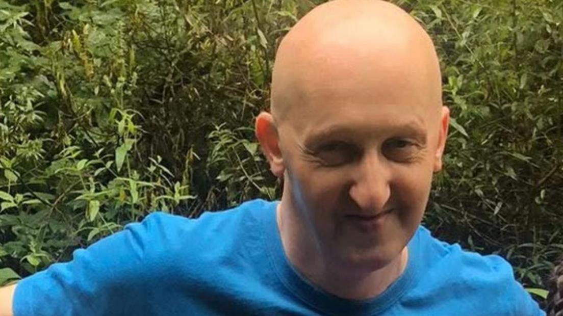 Adrian Daulby has a shaved head and wears a blue T-shirt