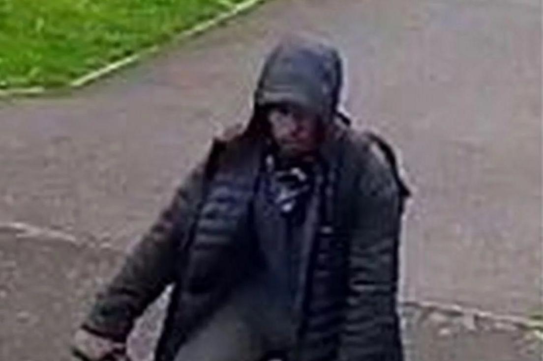 A grainy CCTV still of a hooded man on a pushbike