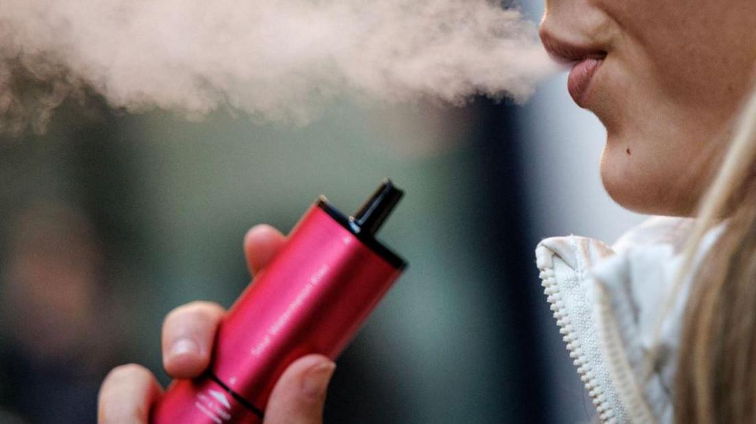 A woman smoking a pink vape