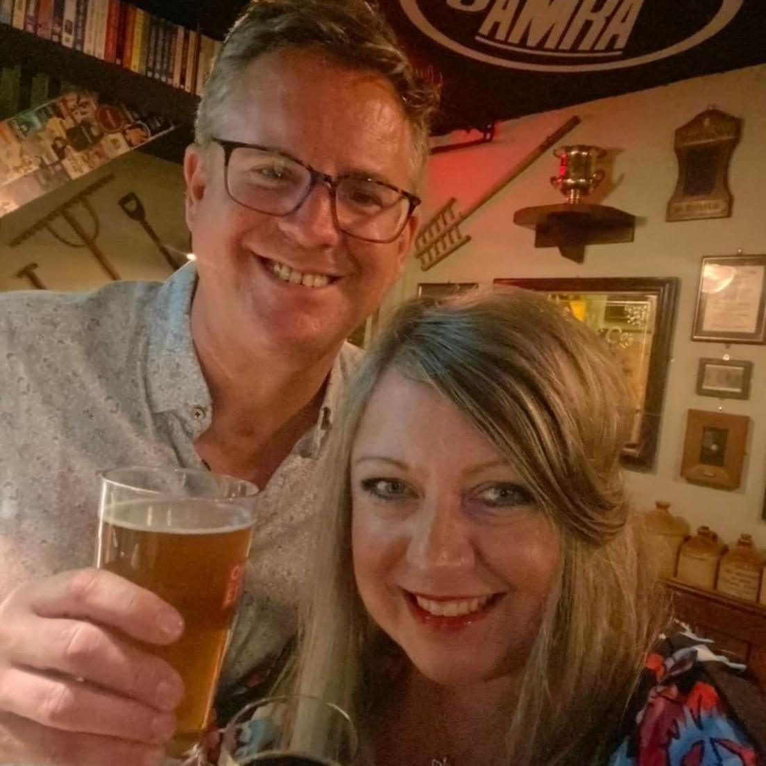 George and Louise Greenaway smiling at the camera while holding drinks