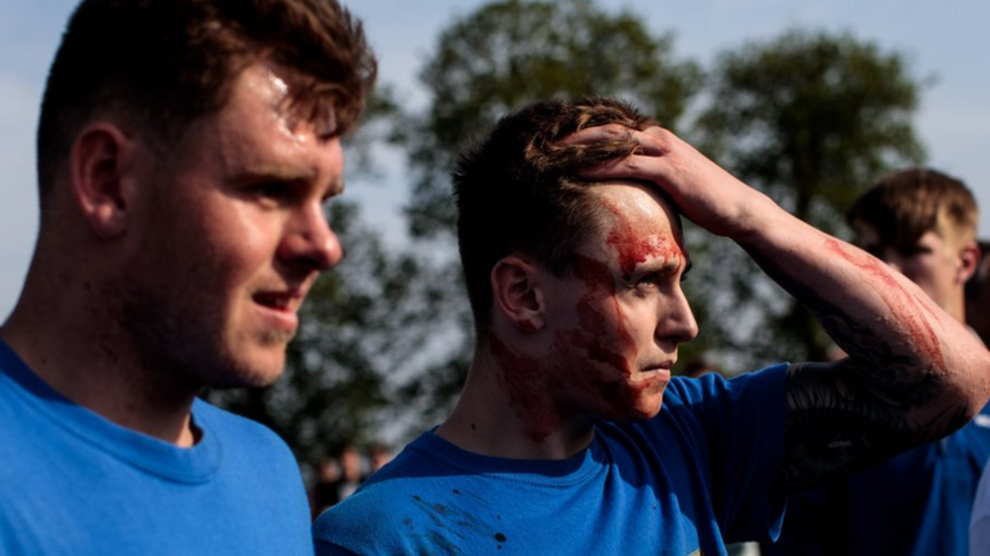 Two bottle kickers, in blue t-shirts. One is holding his head and has blood on his face