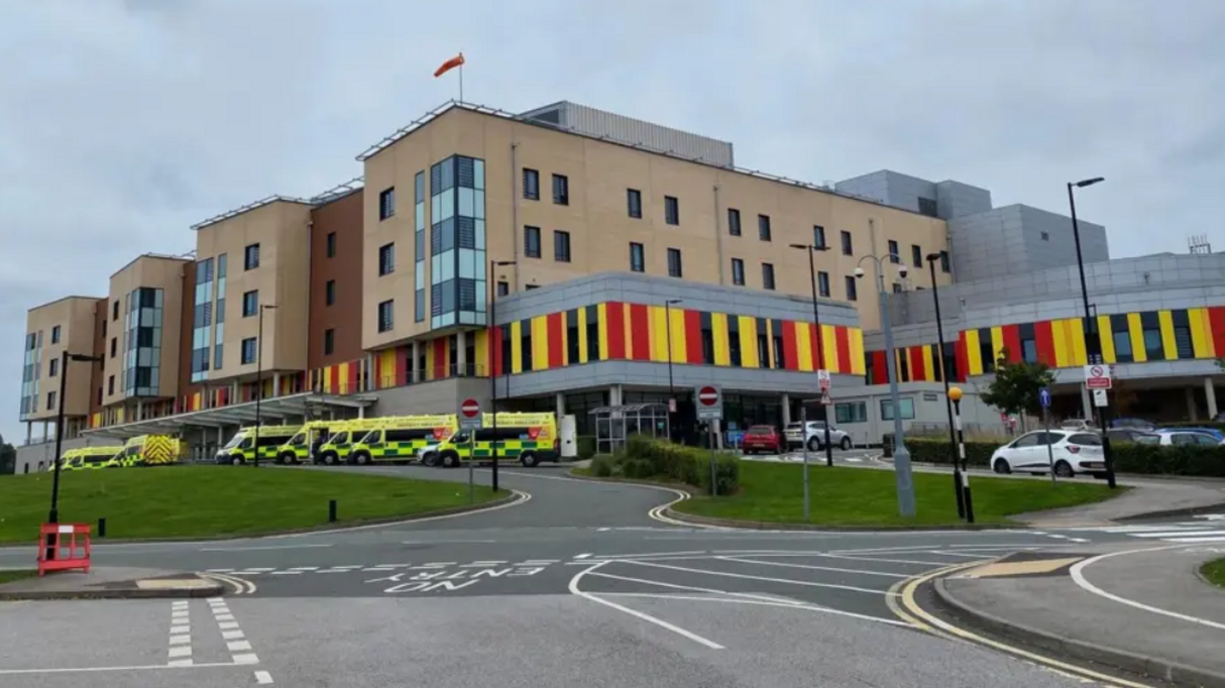 A multi-storey hospital building, with a number of ambulances parked outside.