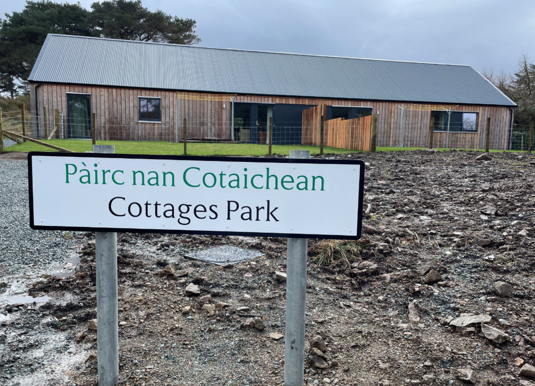 Taighean ùra ann an Ratharsair le soidhne air a bheil sgrìobhte Pàirc nan Cotaichean