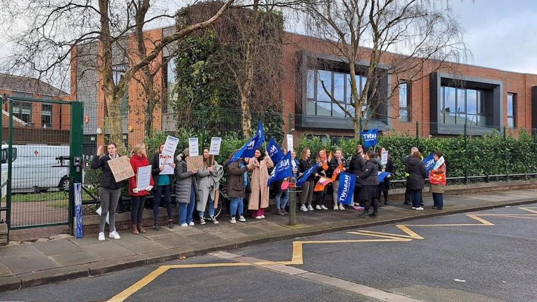 Striking teachers holding banners outside the school gate