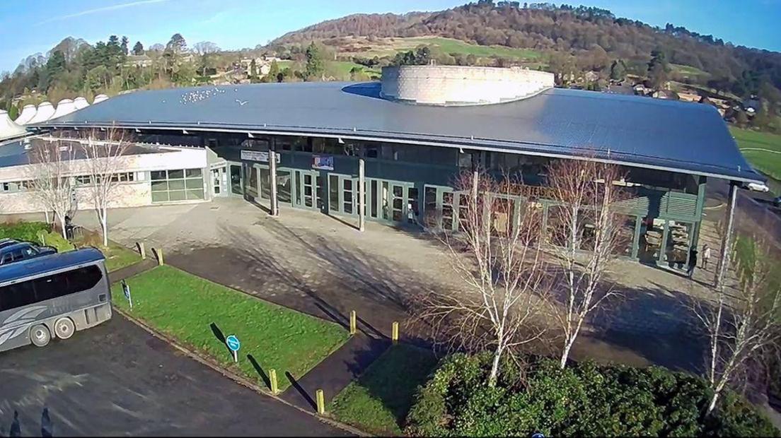 A shot from above of the Agricultural Business Centre, which is a large building with a dark roof and green coloured doors with glass windows. 