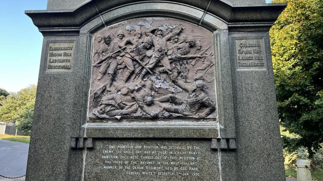 Close-up of the inscription on the Boer War monument. It features a relief of soldiers in battle.