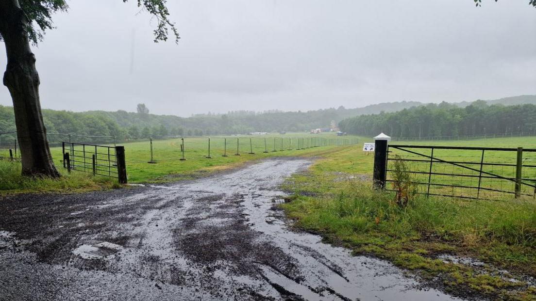 A large puddle at the entrance to a sodden field