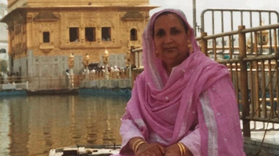 Woman dressed in pink in front of golden temple