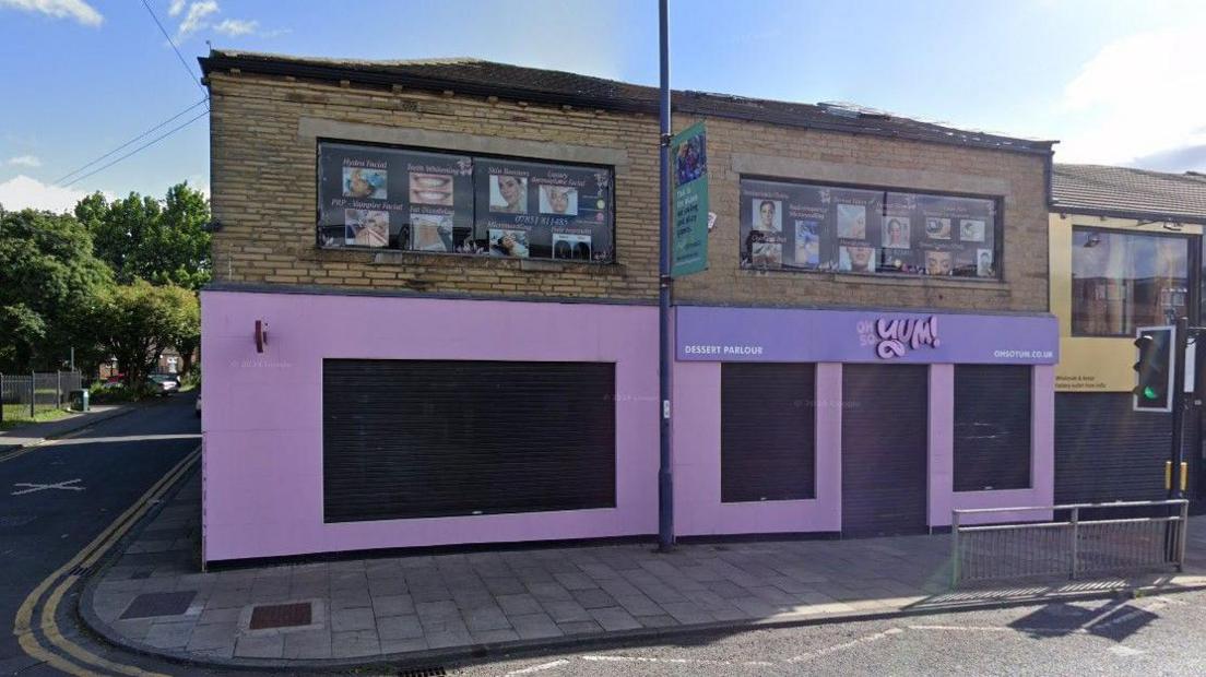 Exterior shot of a closed-down purple shop front on a Bradford high street.